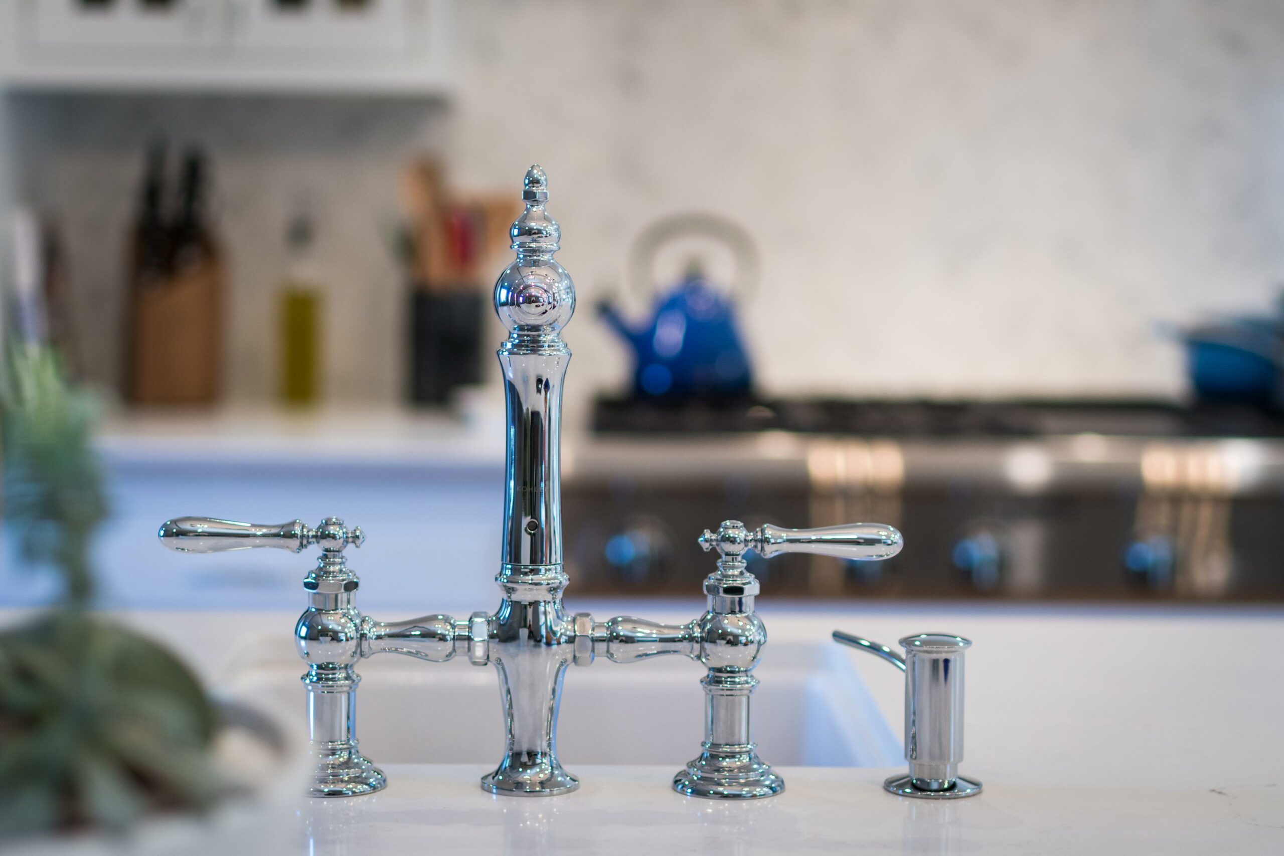 Chrome kitchen faucet on modern white countertop.
