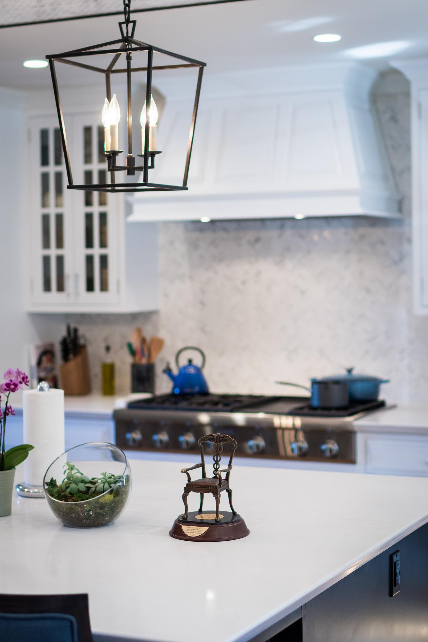 Elegant kitchen interior with modern lighting and marble backsplash.
