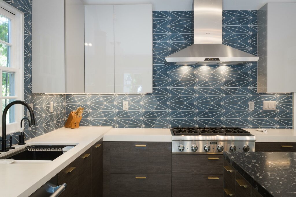 Modern kitchen with geometric backsplash and stainless appliances.