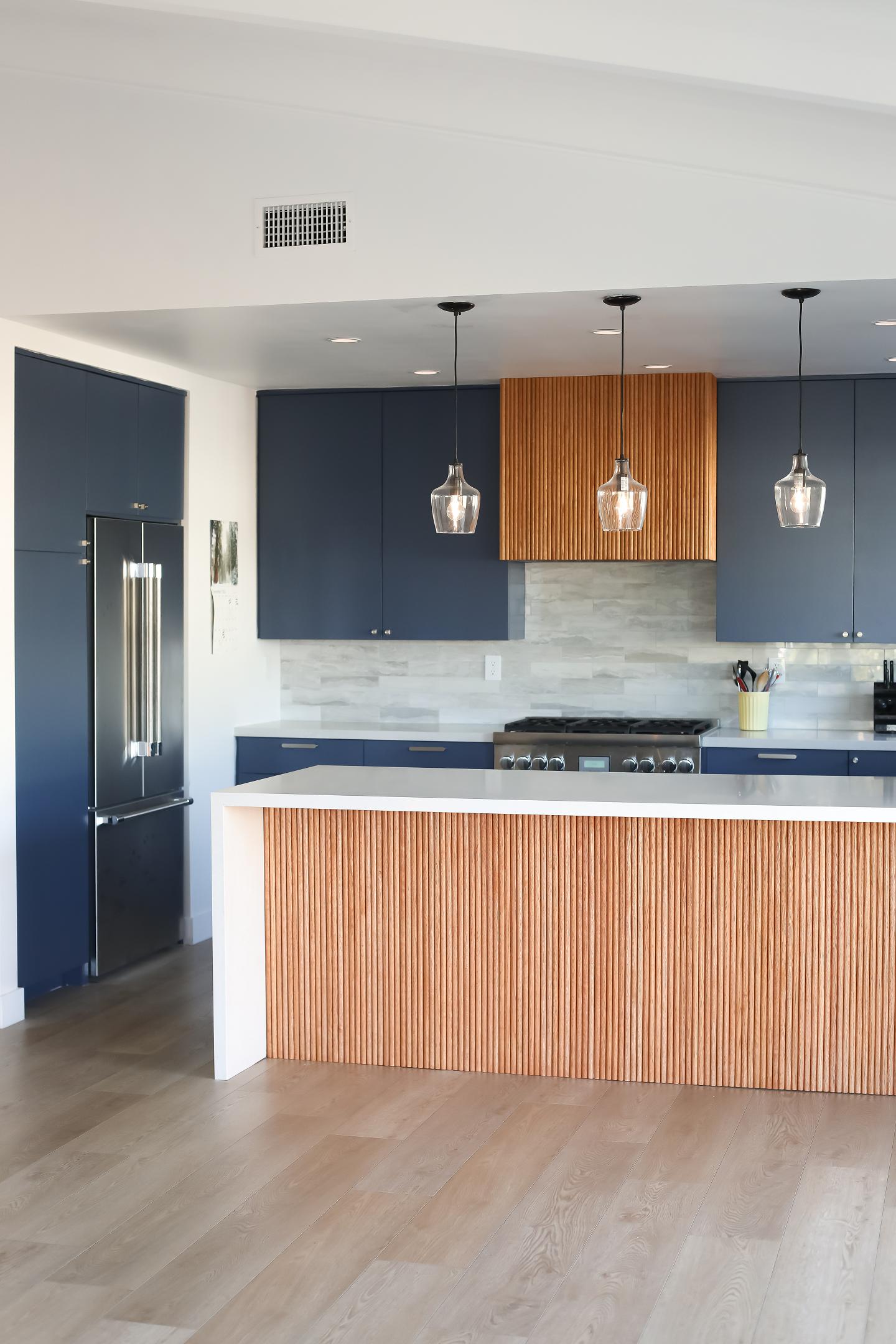 Modern kitchen interior with blue cabinets and wooden accents.