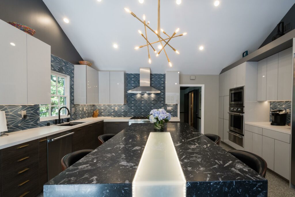 Modern kitchen with marble island and geometric backsplash.
