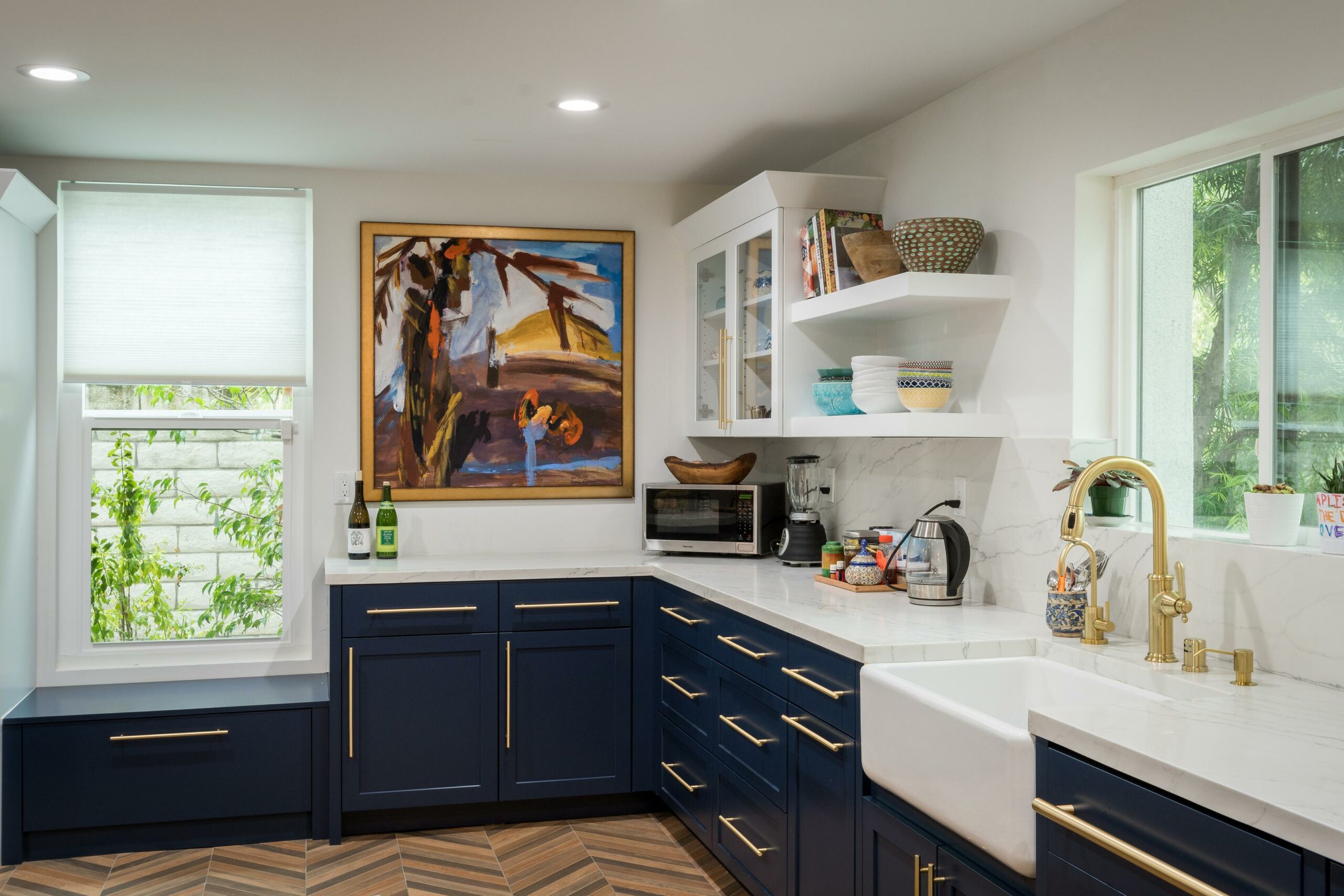Modern kitchen interior with navy cabinets and marble countertop.