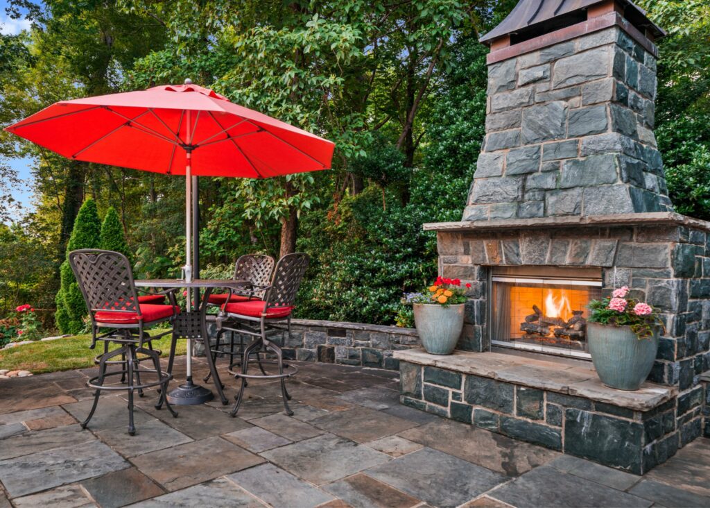Outdoor patio with fireplace and red umbrella.