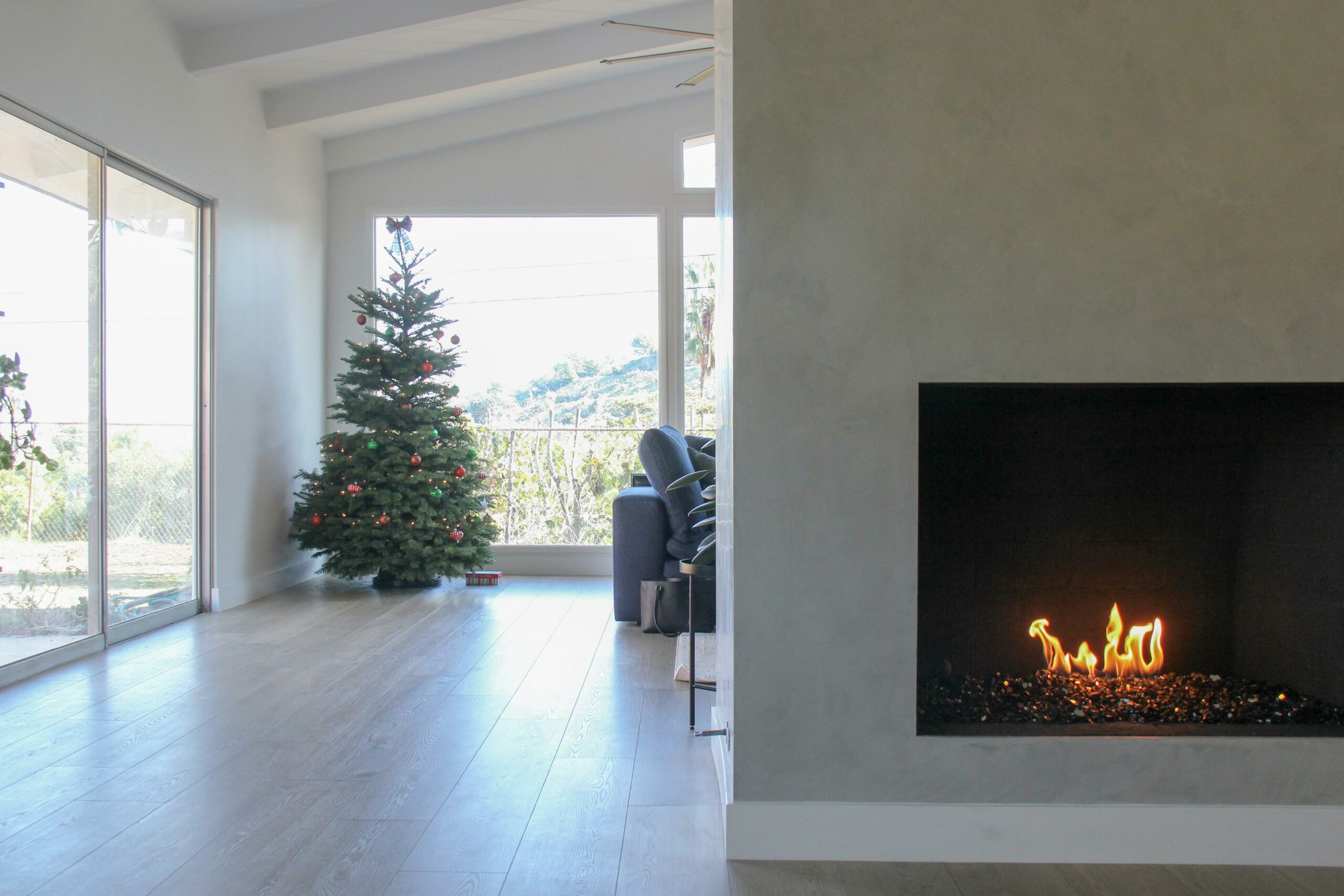 Modern living room with Christmas tree and fireplace.