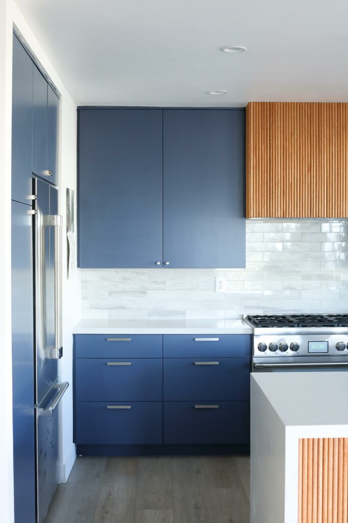 Modern blue kitchen cabinetry with stainless steel appliances.