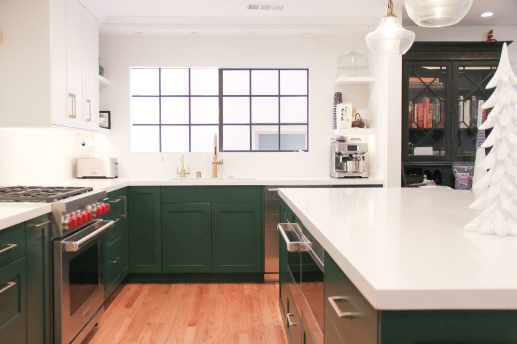 Modern kitchen with green cabinets and white countertops.
