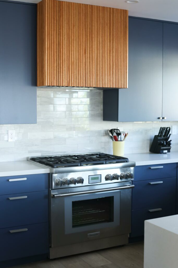 Modern kitchen with stainless steel stove and blue cabinets.