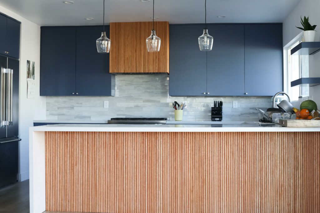 Modern kitchen with blue cabinets and pendant lights.