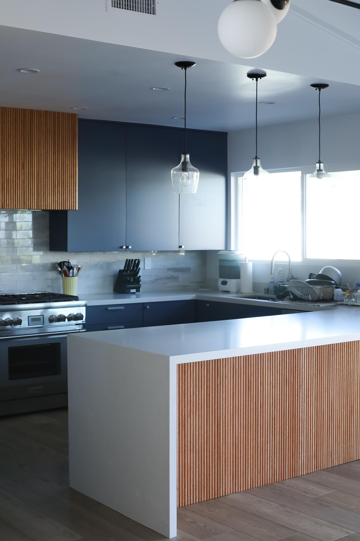 Modern kitchen with pendant lighting and blue cabinets.