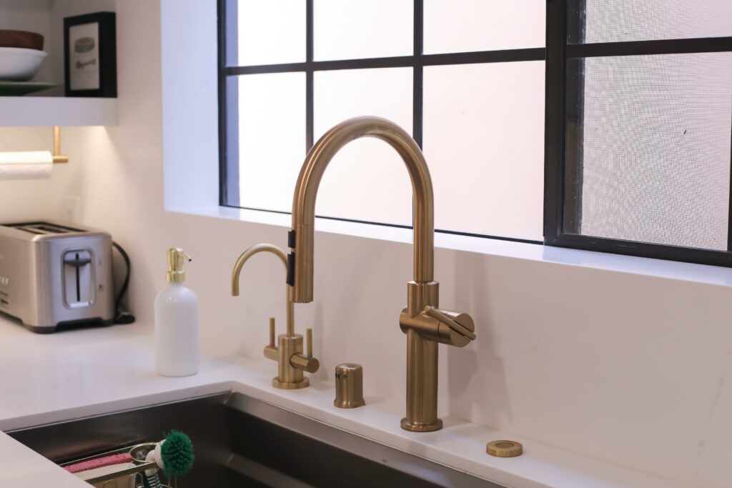 Modern gold kitchen faucet by window.