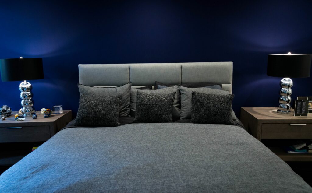 Modern bedroom with blue walls and stylish lamps.