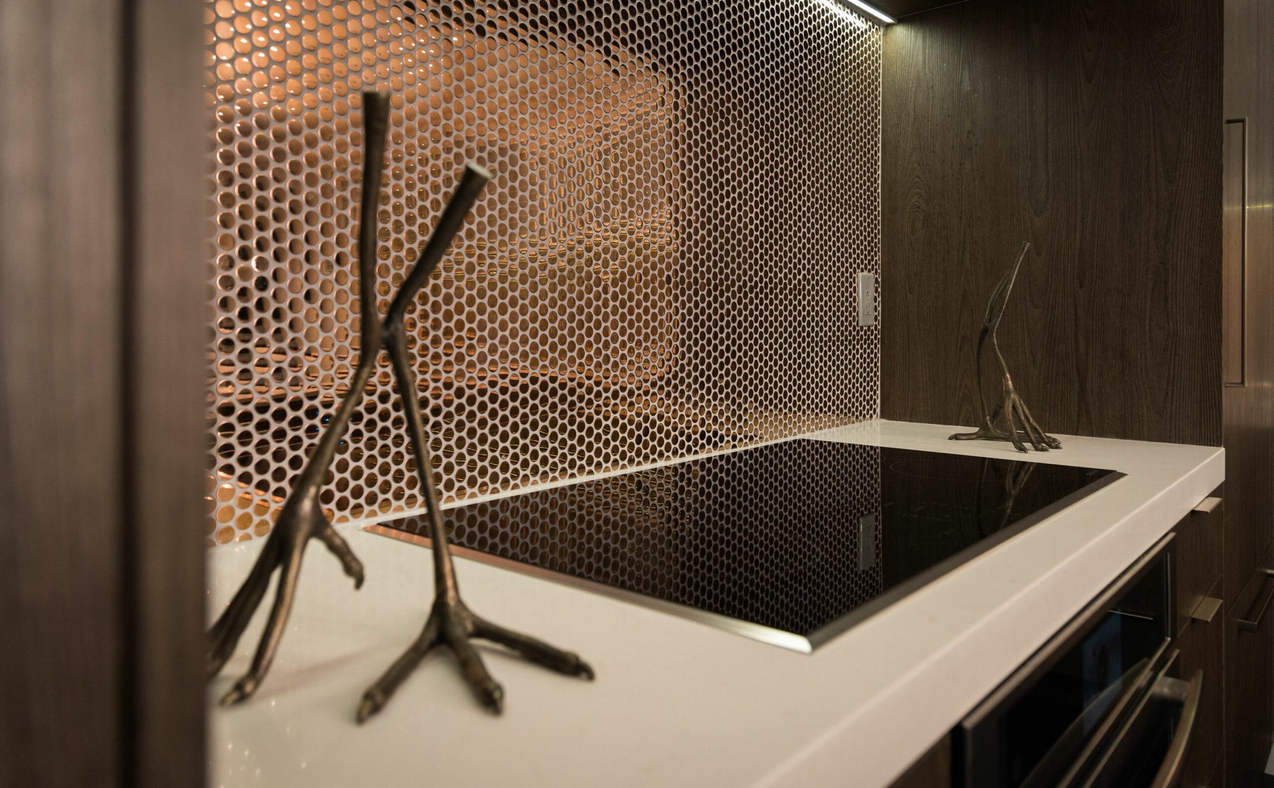 Modern kitchen with decorative metal backsplash and artistic sculptures.