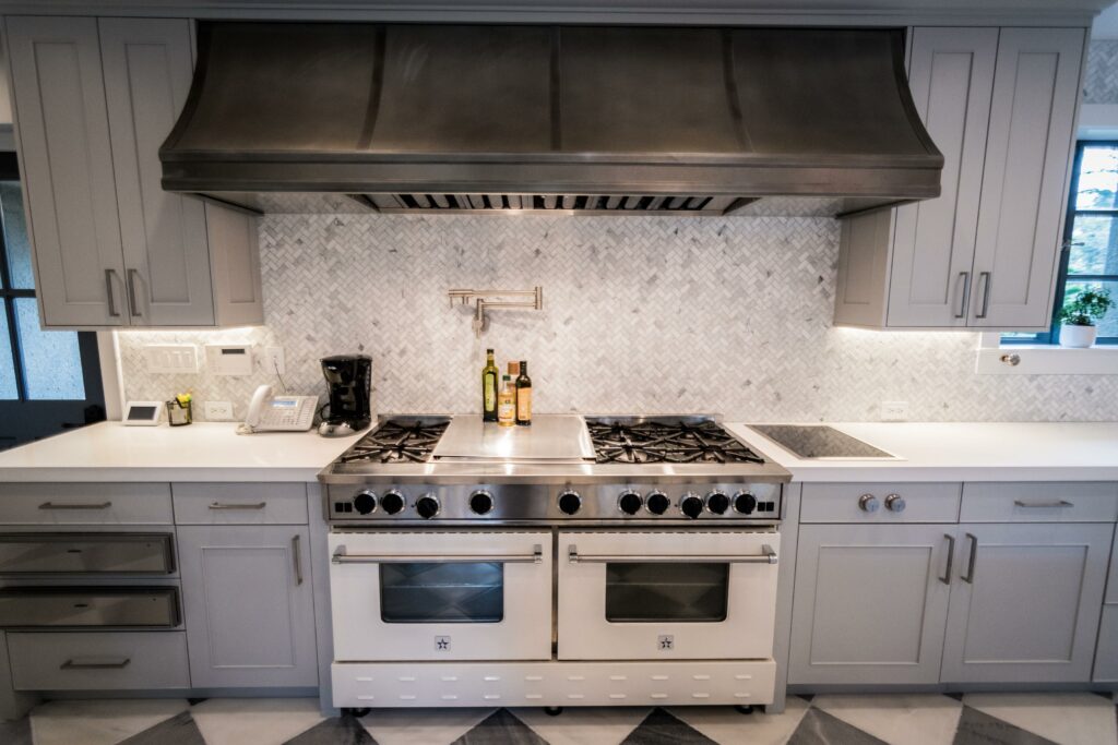 Modern kitchen with stainless steel range and herringbone backsplash.