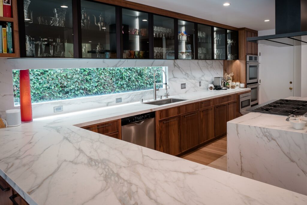 Modern kitchen with marble countertops and wooden cabinets.