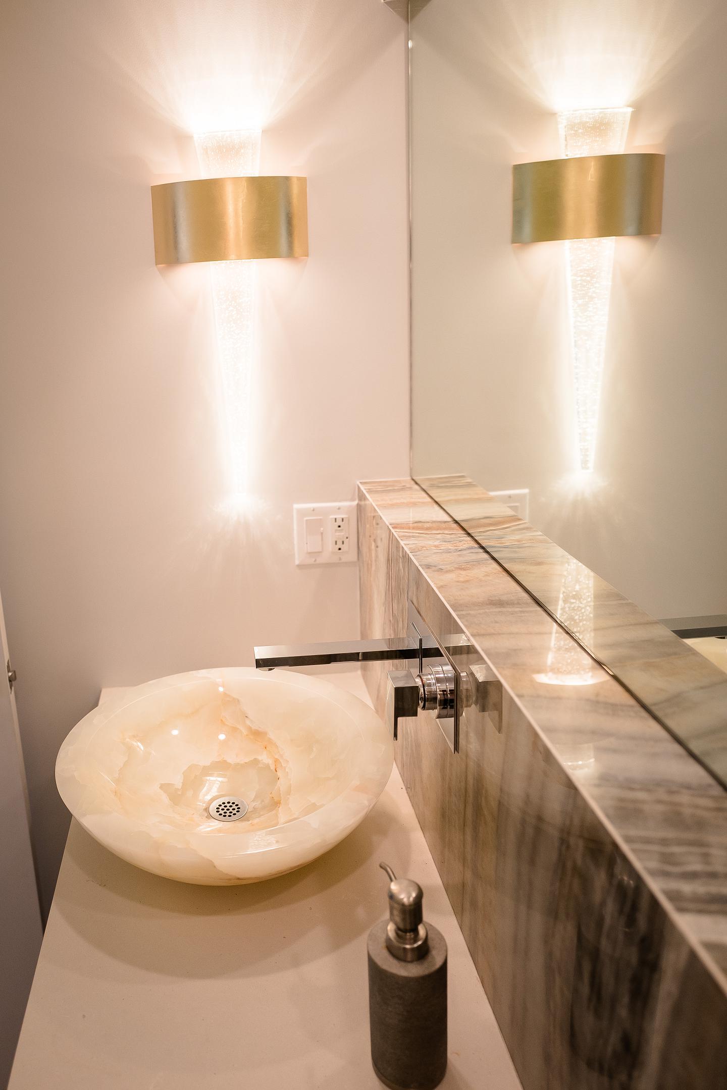 Modern bathroom sink with wall-mounted faucets and lights.