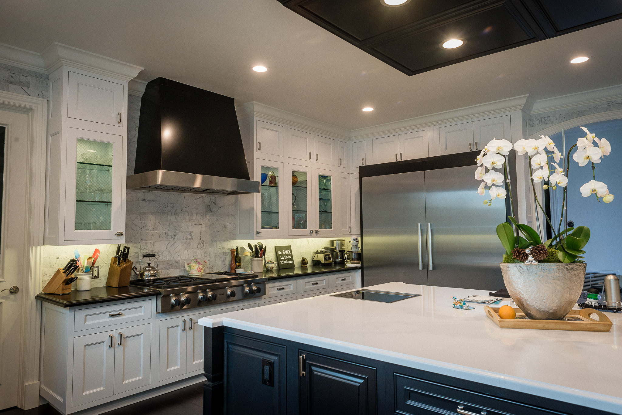 Modern kitchen interior with marble countertops and dark cabinets.