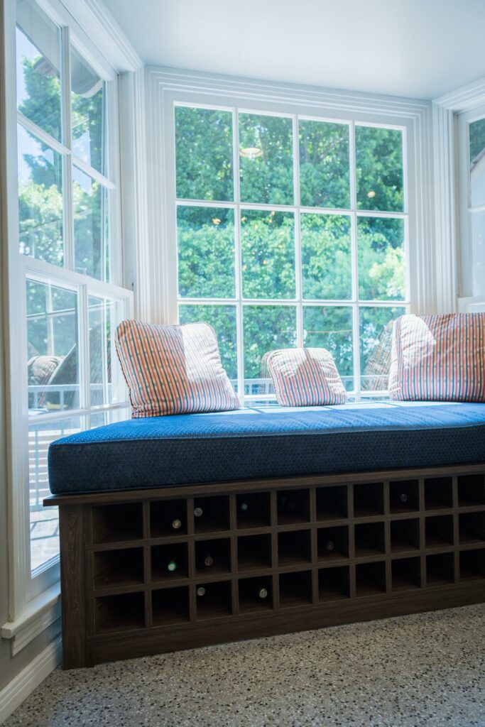 Window seat with storage and striped cushions in sunlight.