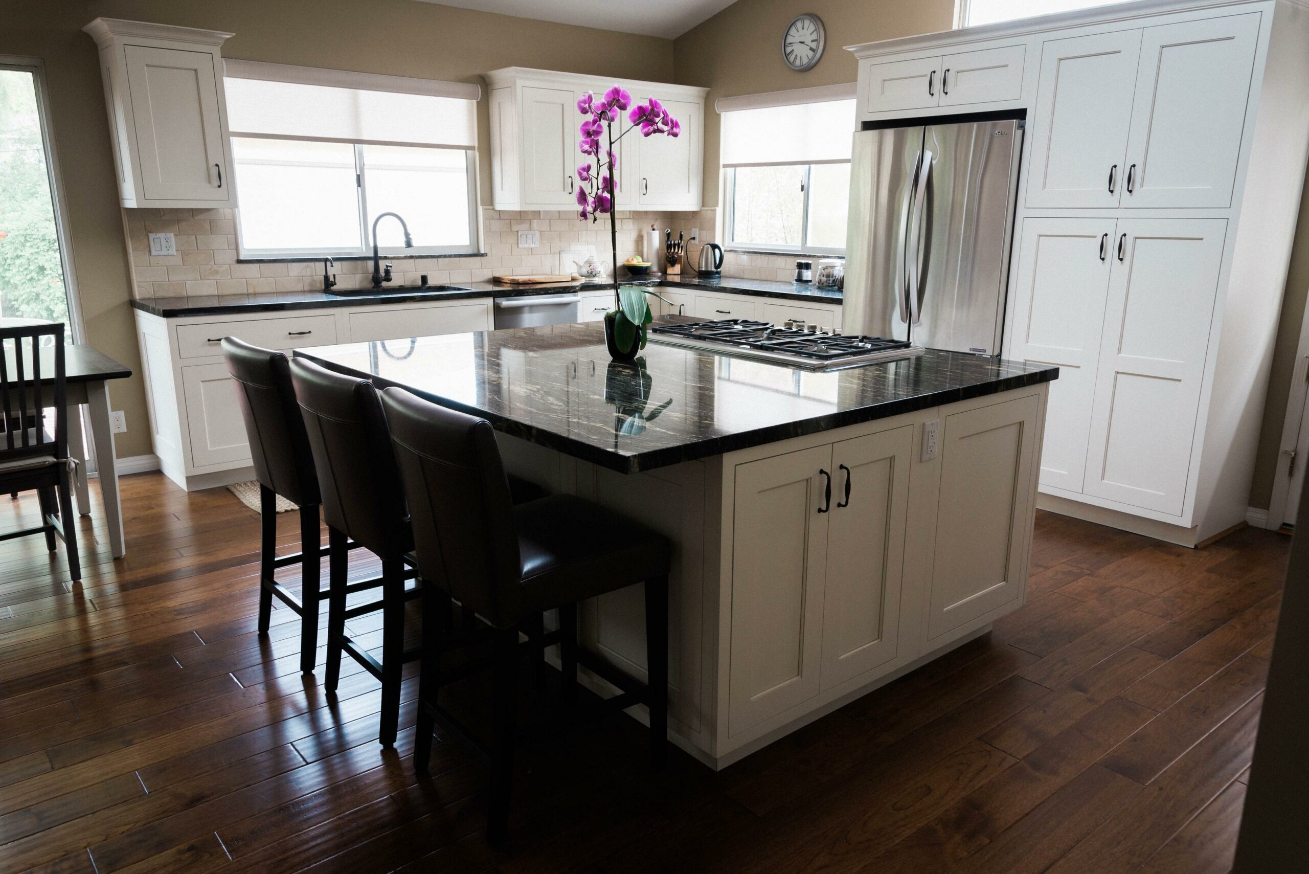 Modern kitchen, white cabinets, granite countertops, hardwood floors.