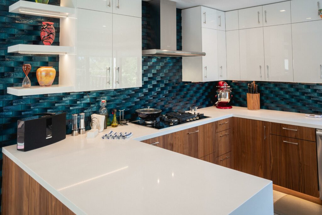 Modern kitchen with blue tile backsplash and white countertops.