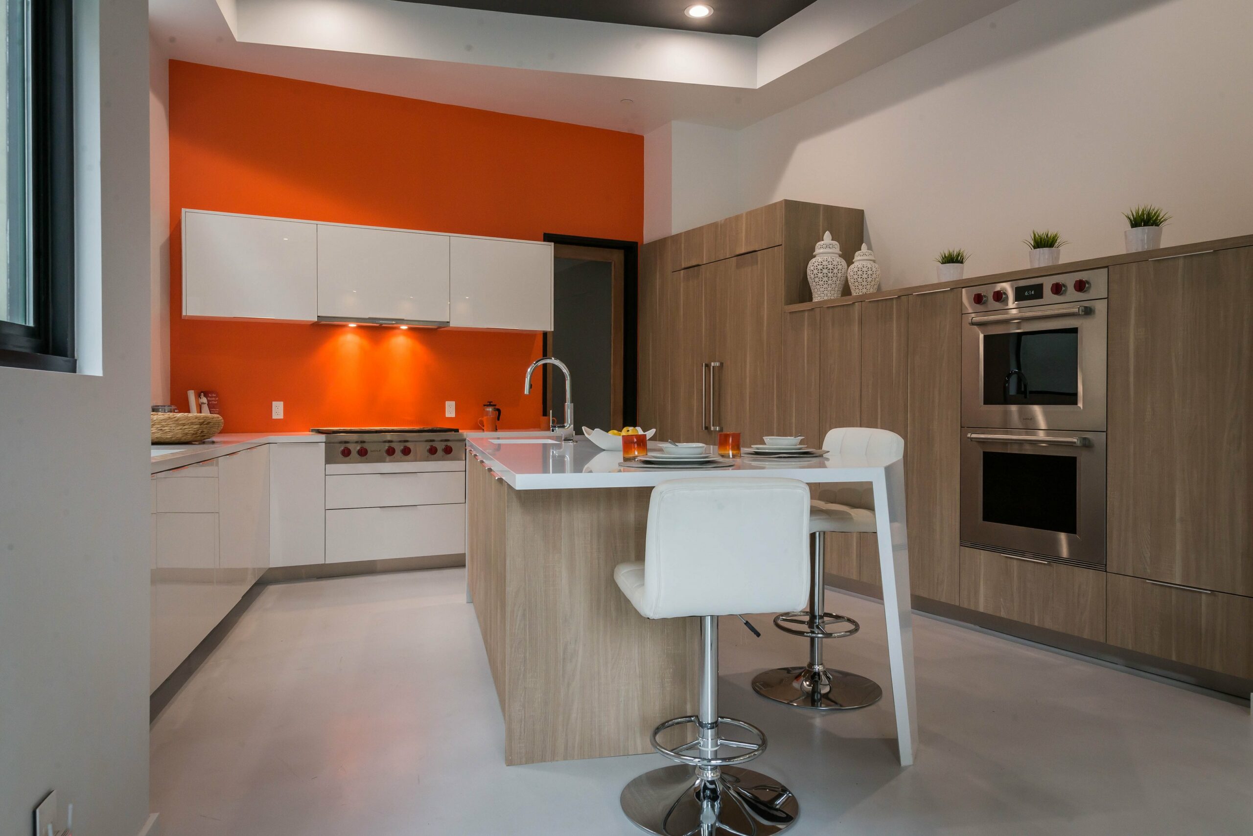 Modern kitchen interior with orange accent wall and breakfast bar.