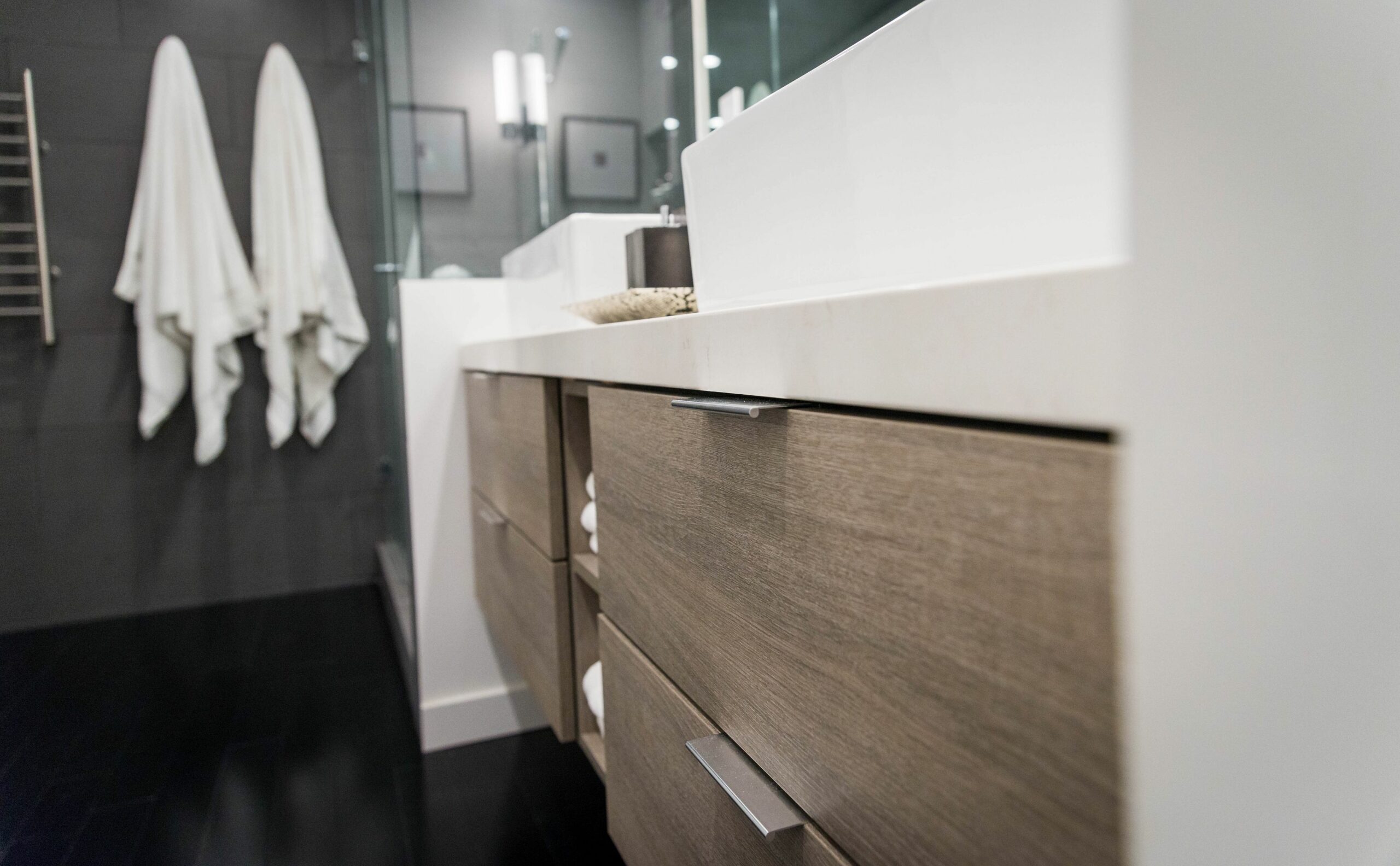 Modern bathroom vanity with towels and black floor.