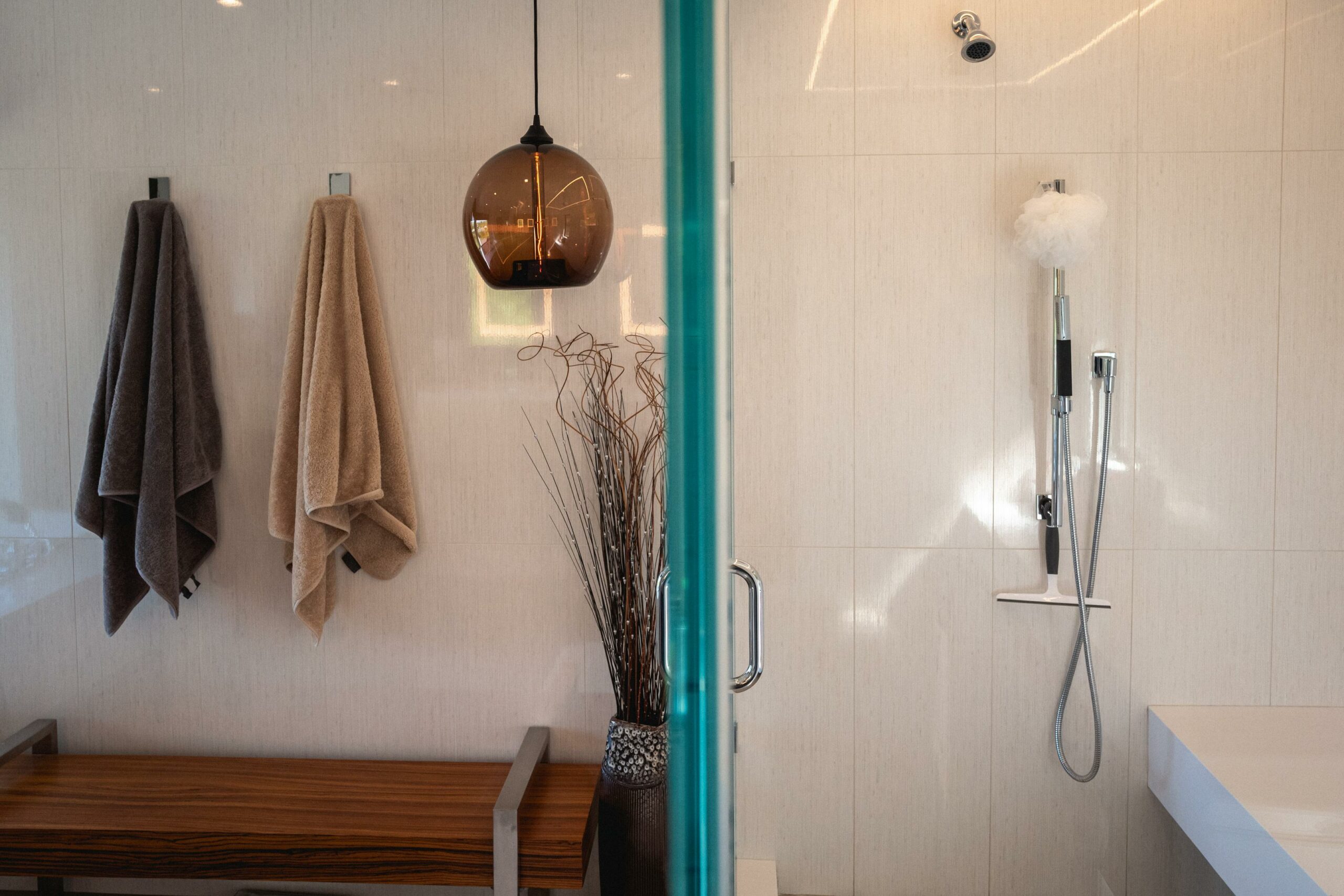 Modern bathroom interior with shower and wooden bench.