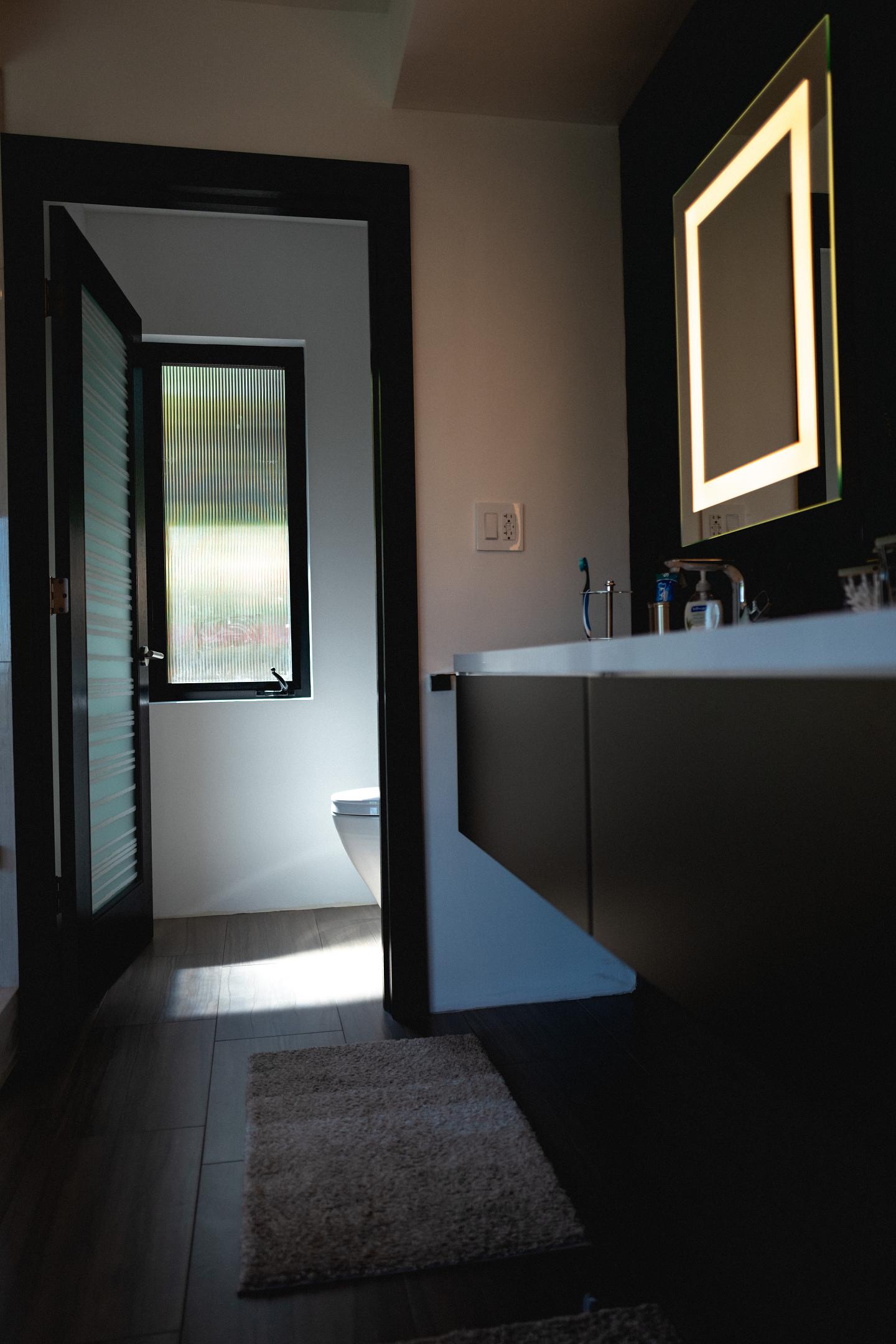Modern bathroom interior with LED mirror and natural light.