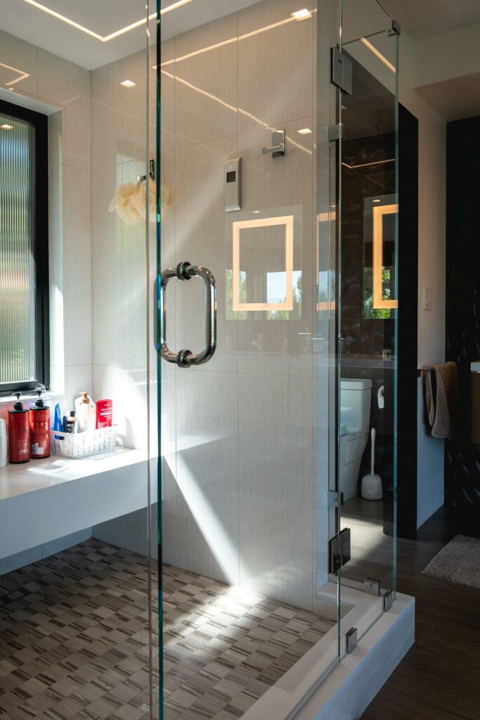 Modern bathroom with glass shower and sunlight.