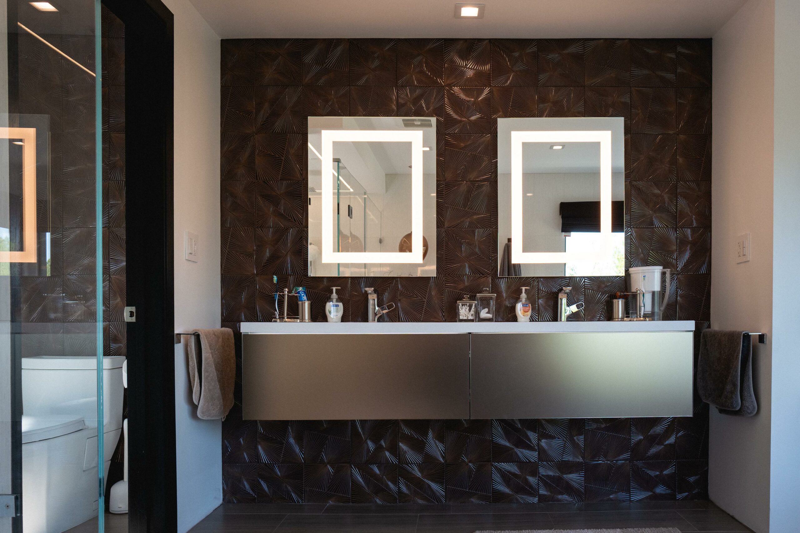 Modern bathroom with textured walls and double vanity mirrors.