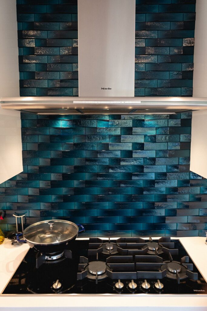 Modern kitchen with blue tile backsplash and gas stove.