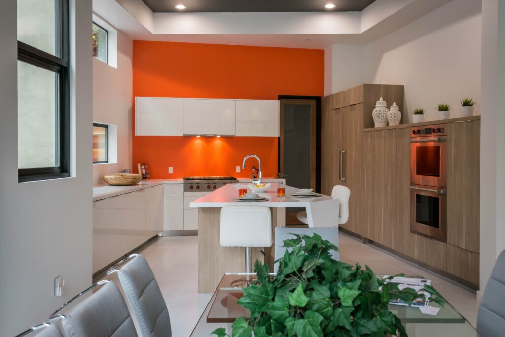 Modern kitchen with orange accent wall and breakfast nook.
