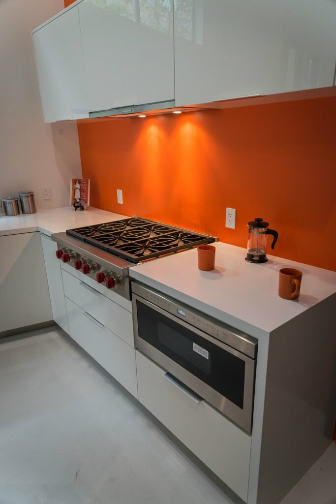 Modern kitchen with orange backsplash and white cabinets.