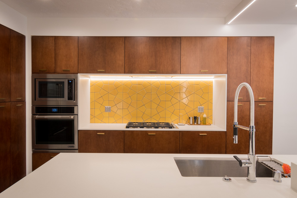 Modern kitchen with yellow backsplash and wooden cabinets.