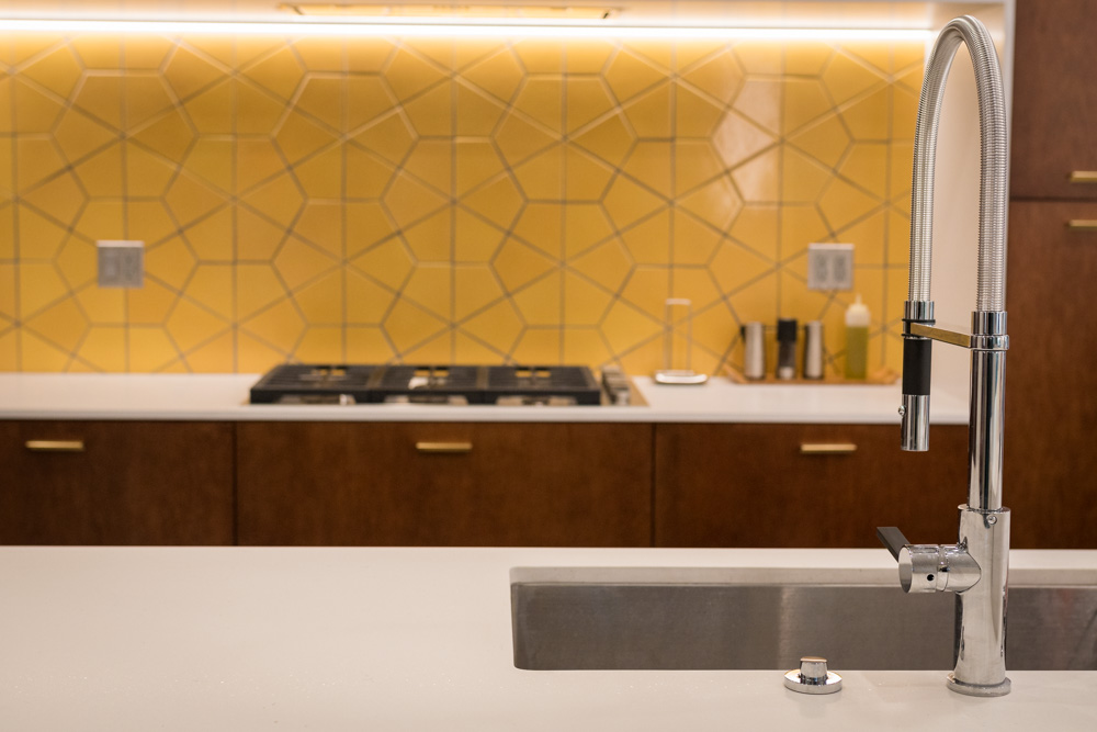 Modern kitchen with yellow backsplash and stainless steel faucet.