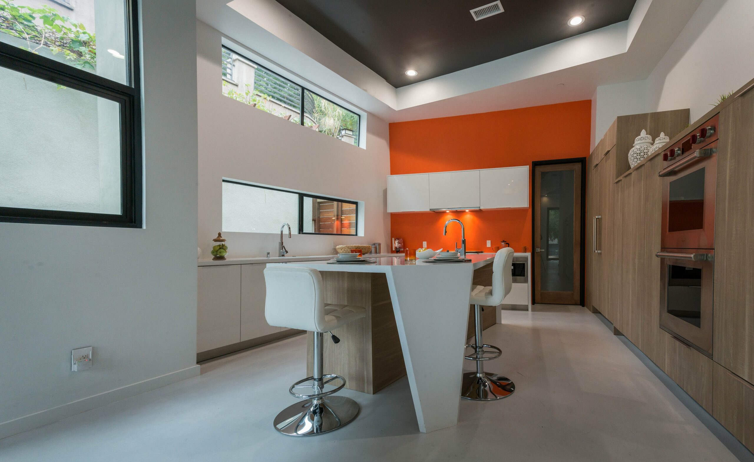 Modern kitchen interior with orange accent wall.