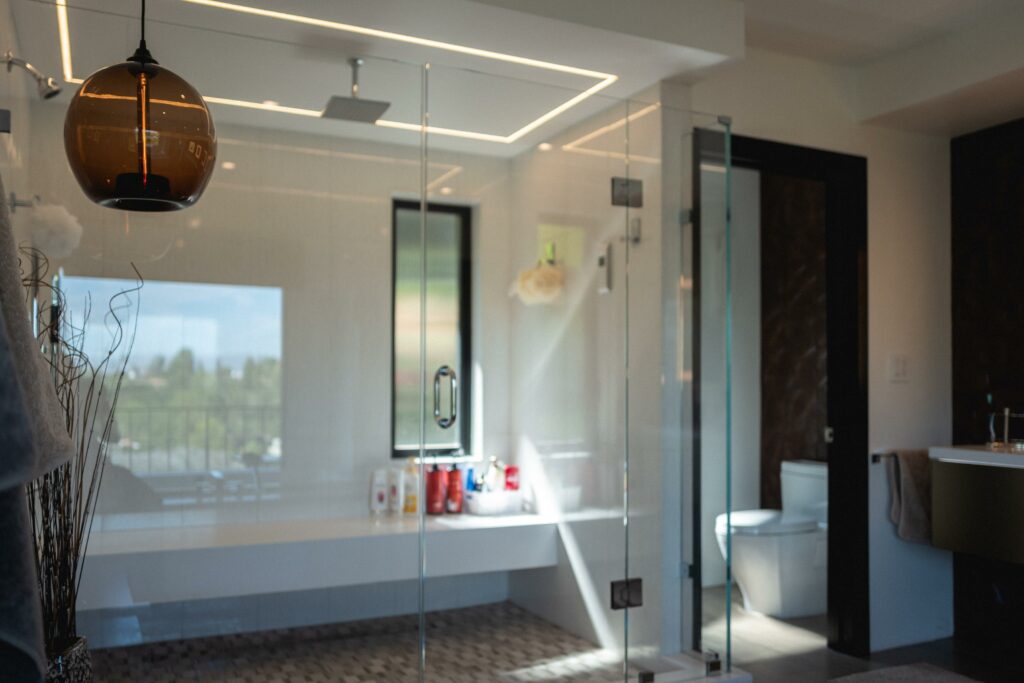 Modern bathroom with glass shower and pendant light.