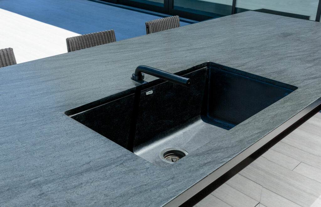 Modern black kitchen sink with faucet on granite counter.