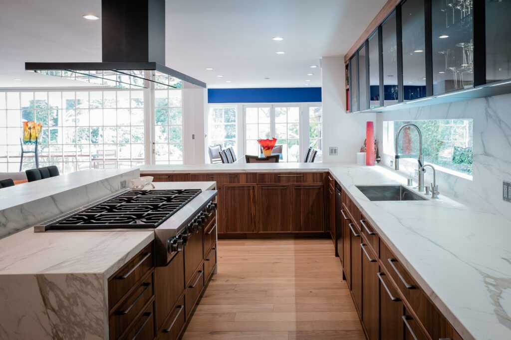 Modern kitchen interior with marble countertops and wood cabinets.