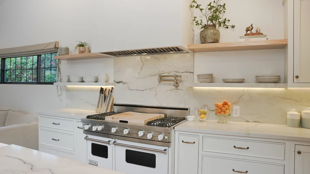 Modern white marble kitchen interior with wooden shelves.