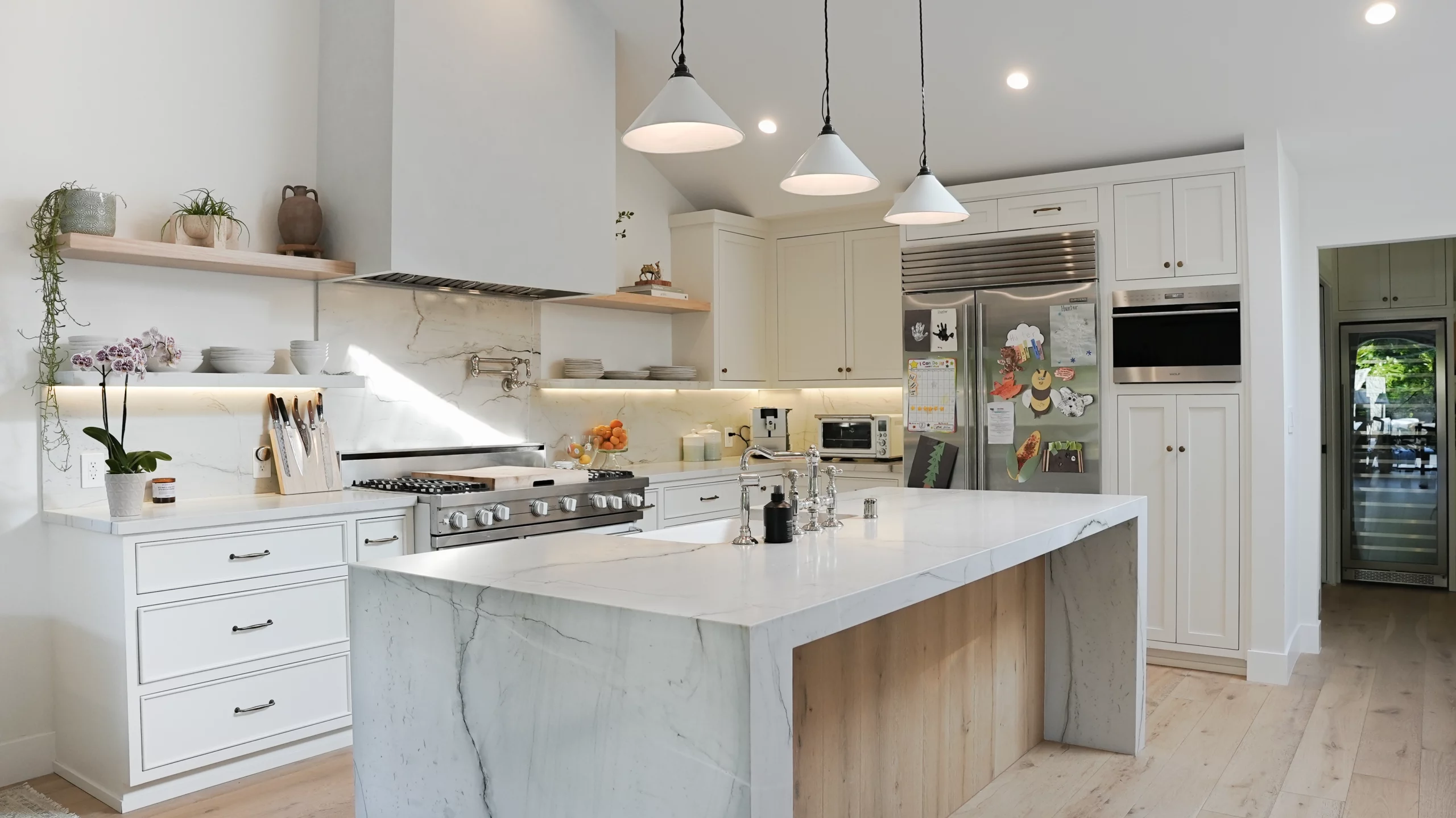 Modern kitchen with white cabinets and marble countertops.